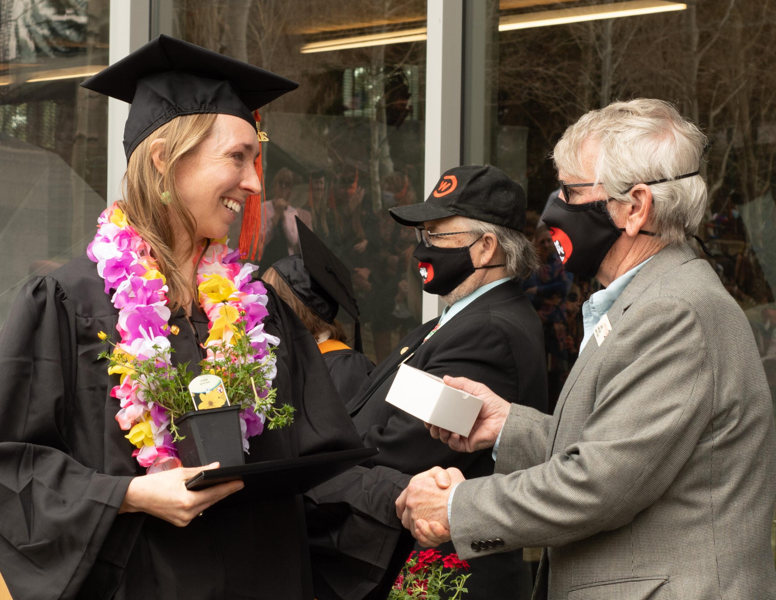 graduate shakes the hands of a CWC board of trustee member